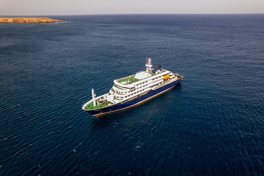 Panorámica aérea del crucero MV Hondius atracado frente al puerto de Praia, la capital de Cabo Verde, el 3 de mayo de 2026. Un brote de "enfermedad respiratoria aguda grave" a bordo de un crucero en el Atlántico ha dejado dos personas fallecidas y una tercera en cuidados intensivos en Johannesburgo, según informó el Ministerio de Salud de Sudáfrica a la AFP el 3 de mayo de 2026. El brote se produjo en el MV Hondius, que viajaba desde Ushuaia, en Argentina, hacia Cabo Verde. (AFP vía Getty Images).