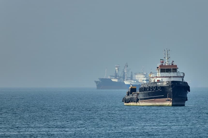 Un remolcador iraní navega en primer plano mientras varios buques de carga permanecen fondeados en el estrecho de Ormuz, frente a Bandar Abbas (Irán), el 4 de mayo de 2026. (Amirhosein Khorgooi/ISNA vía AP)