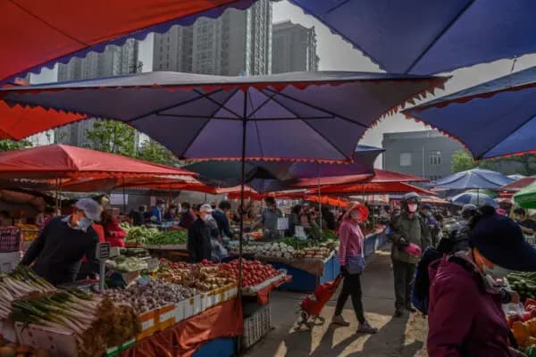 Los vendedores y clientes de frutas y verduras chinos llevan mascarillas protectoras en un mercado local al aire libre de Beijing, el 30 de abril de 2020. (Kevin Frayer/Getty Images).