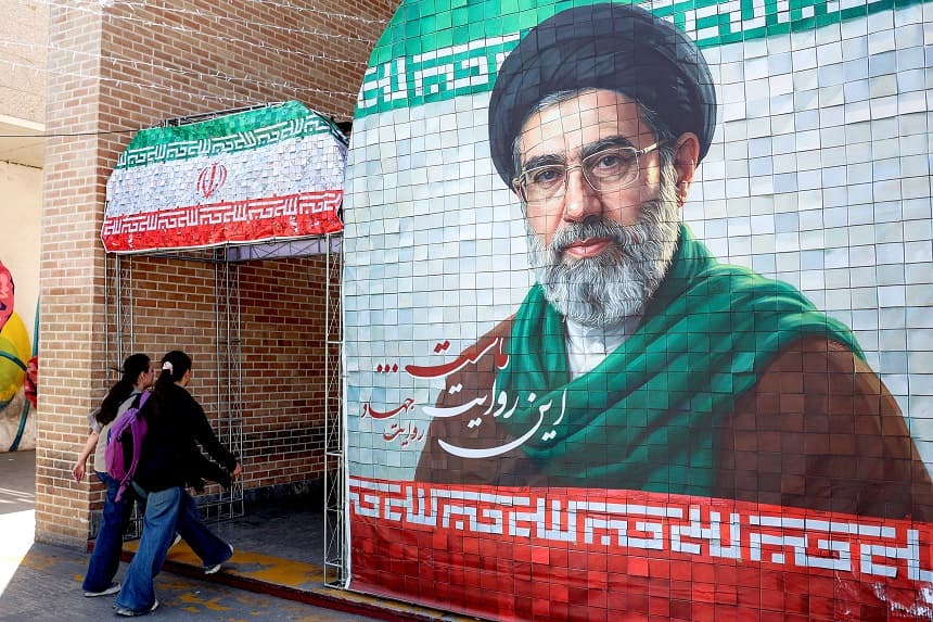 Unas mujeres pasan junto a una pancarta en la que aparece el actual líder supremo de Irán, el ayatolá Mojtaba Jamenei, en una calle de Teherán el 6 de mayo de 2026. (AFP vía Getty Images)