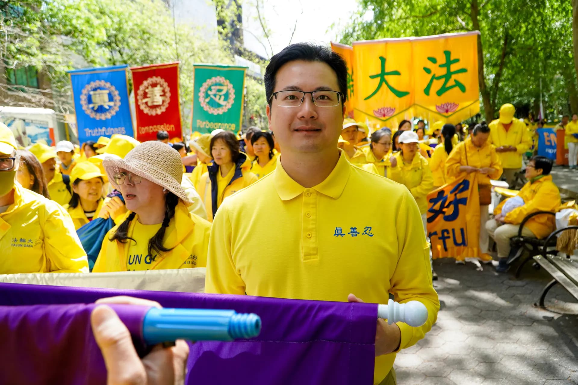 <em>Hugh Huang, de 34 años y originario de Hong Kong, afirmó que practicar Falun Gong le ha ayudado a controlar mejor su ira. Él y otros practicantes se alinearon en la plaza Dag Hammarskjöld para prepararse para un desfile que celebraría el Día Mundial de Falun Dafa, el 13 de mayo de 2026. (Nicholas Zifcak/The Epoch Times).</em>