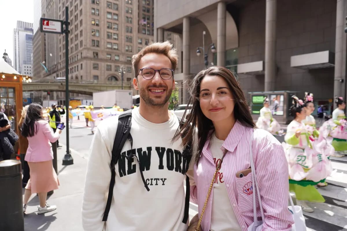 La abogada francesa Emma y su novio, que estaban de vacaciones en Nueva York, vieron el desfile del Día de Falun Dafa en Midtown Manhattan el 13 de mayo de 2026. (. Yu Lili/The Epoch Times)