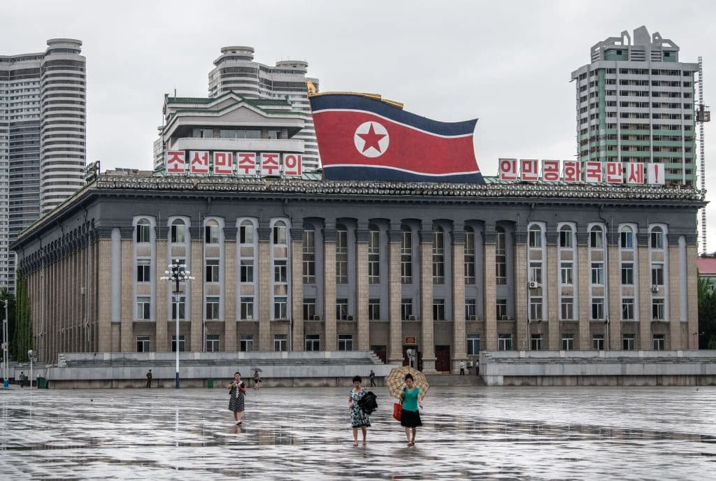 Personaa caminan en la plaza Kim Il-sung delante de una enorme bandera norcoreana en lo alto del edificio del Comité Central del Partido de los Trabajadores de Corea, en Pyongyang, Corea del Norte, el 23 de agosto de 2018. (Carl Court/Getty Images)