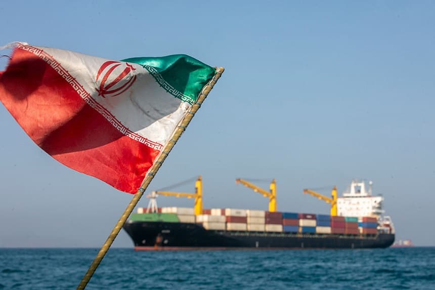Una bandera iraní ondea al viento mientras varios barcos permanecen fondeados el 16 de mayo de 2026 en el estrecho de Ormuz, cerca de la isla de Larak, en Irán. (Majid Saeedi/Getty Images)