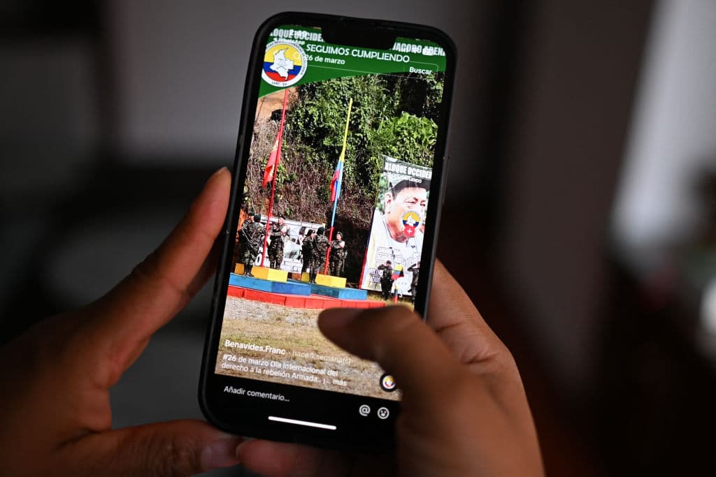 <em>Esta ilustración muestra a una mujer mirando una cuenta de TikTok del Frente Franco-Benavides, perteneciente a la guerrilla disidente de las FARC, en Bogotá, el 2 de abril de 2024. La AFP encontró en TikTok, y en menor medida en Facebook, decenas de cuentas, cientos de publicaciones y varias comunidades de propaganda de grupos armados que responden al Estado Mayor Central (EMC). Unos 3.500 combatientes integran el EMC y se financian principalmente con el narcotráfico, según la inteligencia militar. (Foto de LUIS ACOSTA/AFP vía Getty Images)</em>