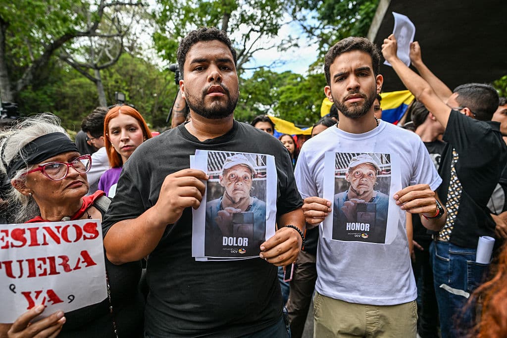 <em>Estudiantes protestan con el retrato de Carmen Navas, madre del fallecido preso político Víctor Quero Navas, tras su muerte en Caracas el 18 de mayo de 2026. La madre del preso político venezolano Víctor Hugo Quero Navas falleció el 17 de mayo de 2026 a los 81 años, pocos días después de confirmar la muerte de su hijo bajo custodia estatal, según informaron sus familiares a la AFP. (Foto de Juan Barreto / AFP vía Getty Images)</em>