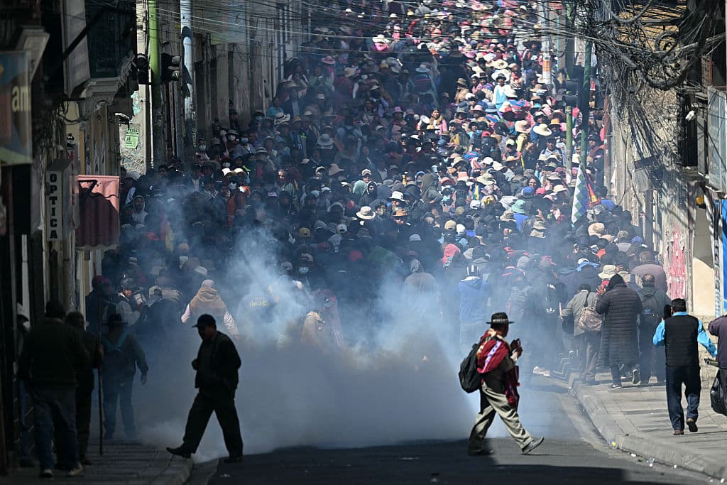 <em>Manifestantes huyen de los gases lacrimógenos durante enfrentamientos con la policía antidisturbios en una protesta que exige la renuncia del presidente boliviano Rodrigo Paz, en La Paz, el 18 de mayo de 2026. Los bolivianos han salido a las calles durante las últimas dos semanas, bloqueando las carreteras de acceso a La Paz e interrumpiendo la entrega de alimentos, medicinas y otros bienes a la capital, mientras exigen mejores salarios, ayuda económica y la renuncia del presidente de centroderecha Rodrigo Paz. (Foto de AIZAR RALDES / AFP vía Getty Images)</em>