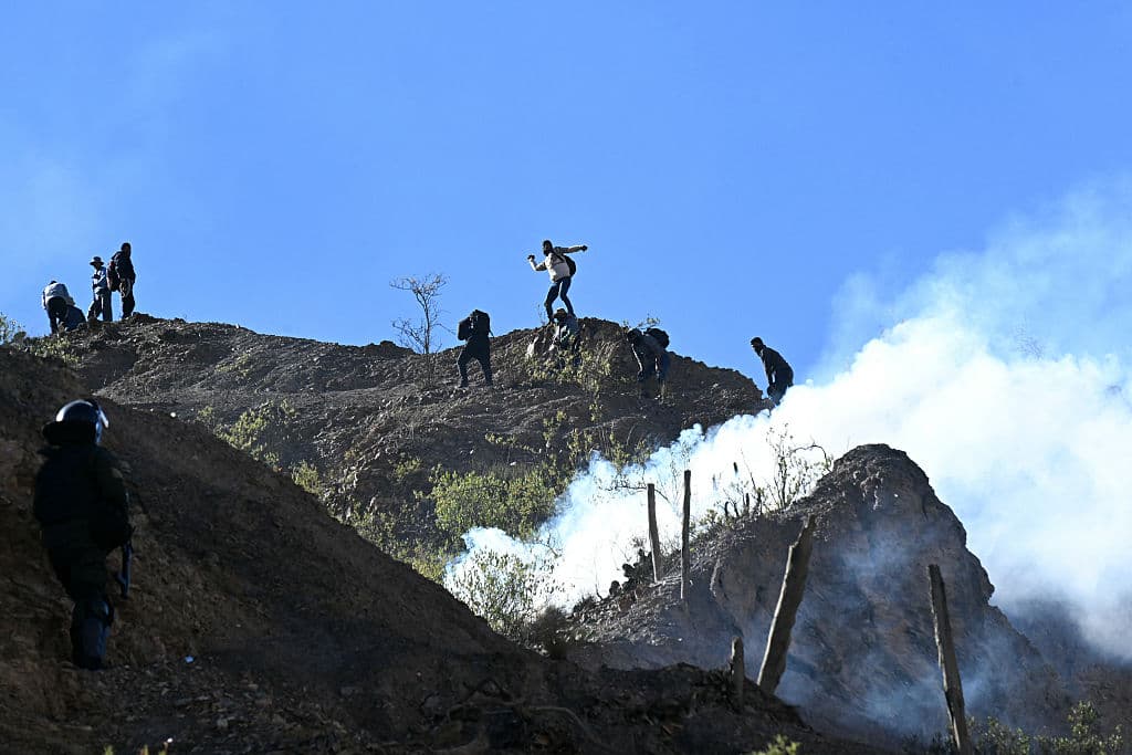 <em>Un manifestante rural lanza piedras desde una ladera durante enfrentamientos con la policía antidisturbios en Lipari, departamento de La Paz, Bolivia, el 16 de mayo de 2026. El gobierno boliviano llegó a un acuerdo el 15 de mayo con miles de mineros que se enfrentaron a la policía en una protesta que paralizó el centro de La Paz. Sin embargo, otros sectores continúan bloqueando las vías de acceso a la ciudad, sede del poder ejecutivo y del Congreso. (Foto de AIZAR RALDES / AFP vía Getty Images)</em>