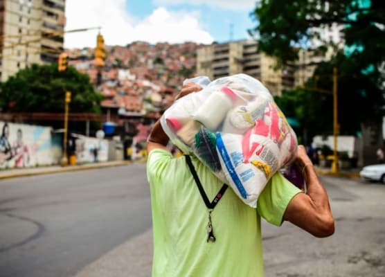 Imagen de archivo. Un hombre carga una bolsa de alimentos básicos al salir de uno de los centros de distribución conocidos como CLAP (Comités Locales de Abastecimiento y Producción), administrados por líderes comunitarios, en Caracas, el 16 de agosto de 2017. (Ronaldo Schemidt / AFP vía Getty Images)