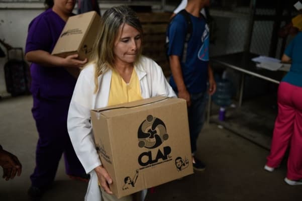Imagen de archivo. Una mujer carga una bolsa de alimentos básicos al salir de uno de los centros de distribución de comida conocidos como CLAP (Comités Locales de Abastecimiento y Producción), administrados por líderes comunitarios, en Caracas, el 16 de agosto de 2017. Los paquetes contienen productos básicos como arroz, harina, pasta, frijoles, aceite, azúcar y leche. (RONALDO SCHEMIDT/AFP vía Getty Images)