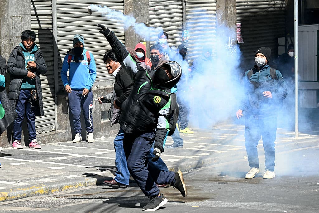 <em>Un manifestante devuelve una granada de gas lacrimógeno a la policía antidisturbios durante una protesta que exige la renuncia del presidente boliviano Rodrigo Paz, en La Paz, el 18 de mayo de 2026. Los bolivianos han salido a las calles durante las últimas dos semanas, bloqueando las carreteras de acceso a La Paz e interrumpiendo la entrega de alimentos, medicinas y otros bienes a la capital, mientras exigen mejores salarios, ayuda económica y la renuncia del presidente de centroderecha Rodrigo Paz en medio de una grave crisis económica. (Foto de AIZAR RALDES / AFP vía Getty Images)</em>
