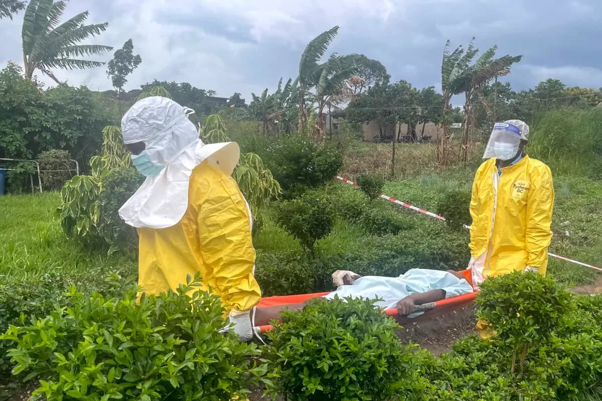 Después de que manifestantes incendiaran un hospital, el personal médico, equipado con equipo de protección personal, transporta a un paciente en un hospital de Rwampara, en el suroeste de Uganda, durante el brote de ébola, el 21 de mayo de 2026. (Seros Muyisa /AFP)