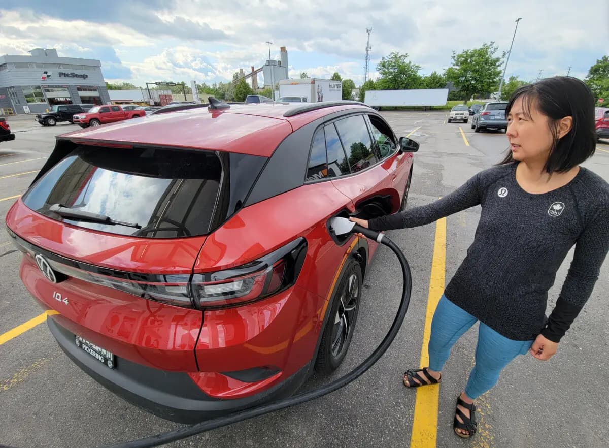 Una mujer utiliza una estación de carga de vehículos eléctricos en Canadian Tire en Scarborough, Ontario, el 14 de junio de 2023. (The Canadian Press/Doug Ives)