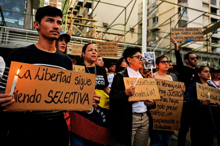 Un joven sostiene un cartel en el que se lee: "La libertad sigue siendo selectiva", durante una vigilia convocada por familiares de presos políticos en Caracas el 22 de mayo de 2026. (Maryorin Mendez / AFP vía Getty Images)