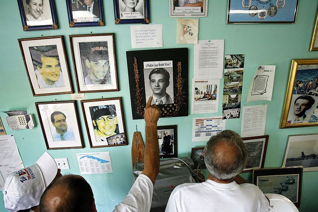 Voluntarios del Movimiento Democracia observan fotografías de personas que murieron o fueron asesinadas mientras se oponían al gobierno de Castro en Cuba, en su oficina el 2 de agosto de 2006 en Miami, Florida. La fotografía del centro es de Pedro Luis Boitel, quien murió de un ataque de hambre mientras estaba encarcelado en Cuba en 1972. Las cuatro fotografías de la izquierda son de los pilotos de Hermanos al Rescate, derribados por aviones cubanos en 1996. Movimiento Democracia ha estado preparando una flotilla de barcos para dirigirse a Cuba tras enterarse de que Fidel Castro había entregado el poder a su hermano menor, Raúl Castro, mientras este recibía tratamiento médico por una hemorragia intestinal. (Foto de Chip Somodevilla/Getty Images)