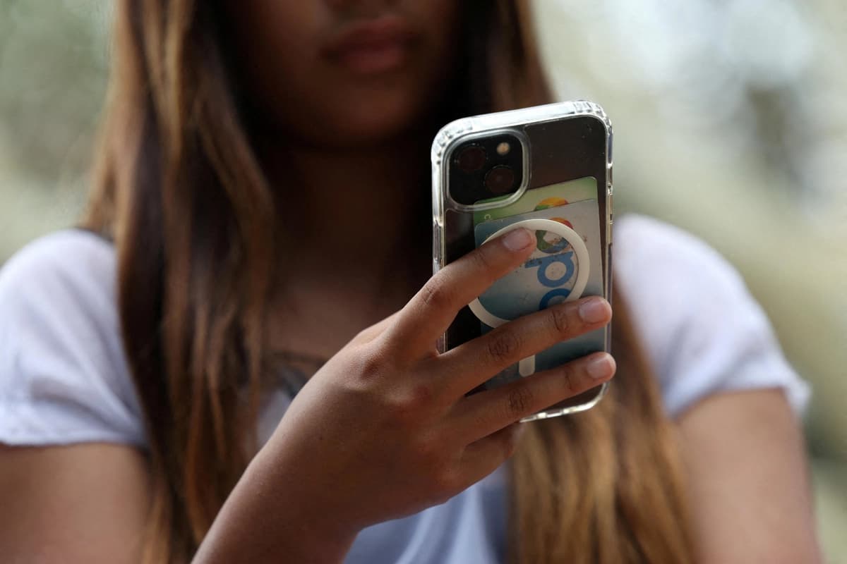 <em>Una adolescente sostiene un teléfono móvil en Sídney el 10 de diciembre de 2025. (Hollie Adams/Reuters).</em>