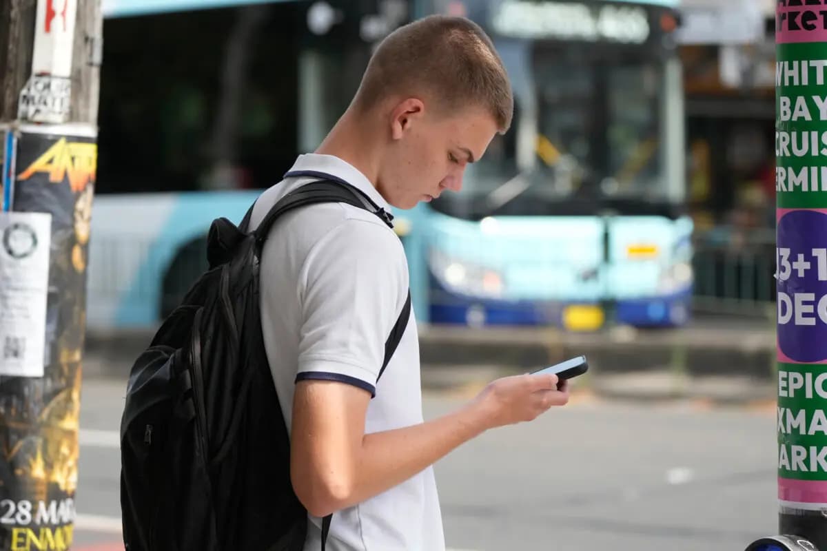 <em>Un adolescente aparece en una fotografía usando su teléfono mientras espera para cruzar la calle en Sídney, el 8 de diciembre de 2025. (Foto AP/Rick Rycroft).</em>