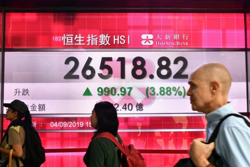 Imagen Ilustrativa: Peatones caminan junto a un panel con la actividad del índice Hang Seng en Hong Kong el 4 de septiembre de 2019, cuando la bolsa subió tras informes sobre el retiro de un polémico proyecto de ley de extradición. (Anthony Wallace / AFP).