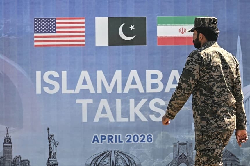 A Pakistani Ranger walks past a billboard for the U.S.–Iran peace talks in Islamabad on April 12, 2026. (Farooq Naeem/AFP via Getty Images)