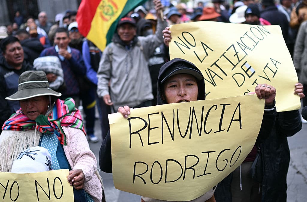 <em>Manifestantes con carteles durante protesta contra el presidente Rodrigo Paz en La Paz, el 25 de mayo de 2026. La presidencia de Paz se ha visto sacudida por protestas arraigadas, centradas en La Paz, la capital administrativa de Bolivia, que han provocado el bloqueo de carreteras y la consiguiente escasez de alimentos, combustible y medicinas. (Foto de MARVIN RECINOS / AFP vía Getty Images)</em>