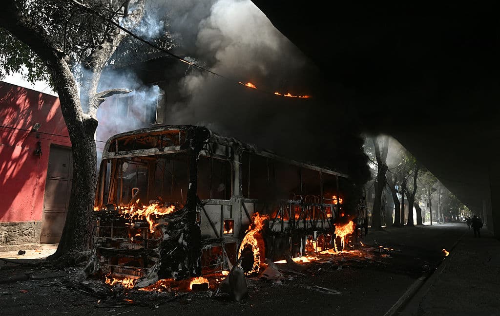 <em>Vista de un autobús incendiado presuntamente por narcotraficantes durante un operativo policial en el centro de Río de Janeiro, Brasil, el 18 de marzo de 2026. Los enfrentamientos entre la policía y grupos criminales fuertemente armados, como el Comando Vermelho, son frecuentes en las favelas, cuyos territorios están bajo el control de estas bandas. Los autobuses que pasan cerca de las entradas de las favelas son secuestrados por los criminales en represalia y colocados en las carreteras para bloquear el avance de las fuerzas del orden. Sembrar el caos en la ciudad de esta manera también es una demostración de fuerza. (Foto de Mauro PIMENTEL / AFP vía Getty Images)</em>