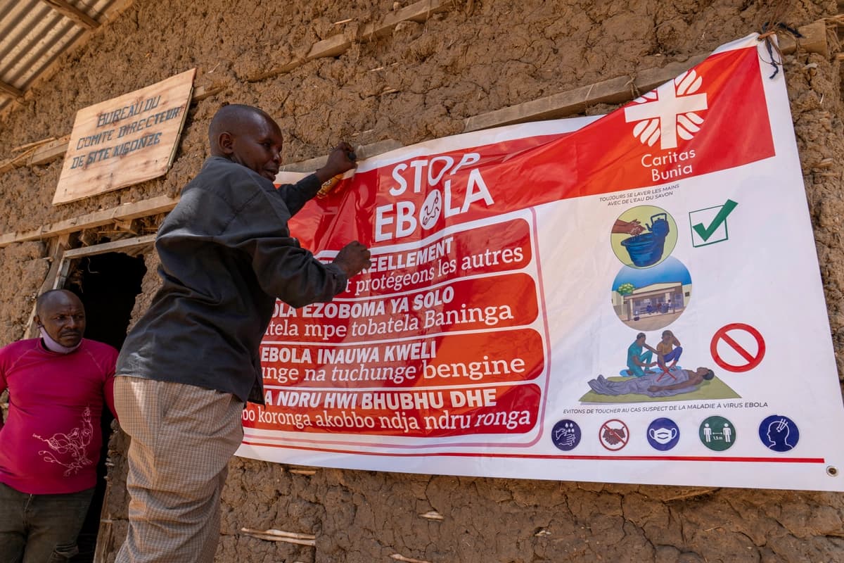 <em>Un hombre cuelga una pancarta de concientización sobre el ébola en el campamento de Kigonze en Bunia, Congo, el 28 de mayo de 2026. (Glody Murhabazi/AFP vía Getty Images).</em>