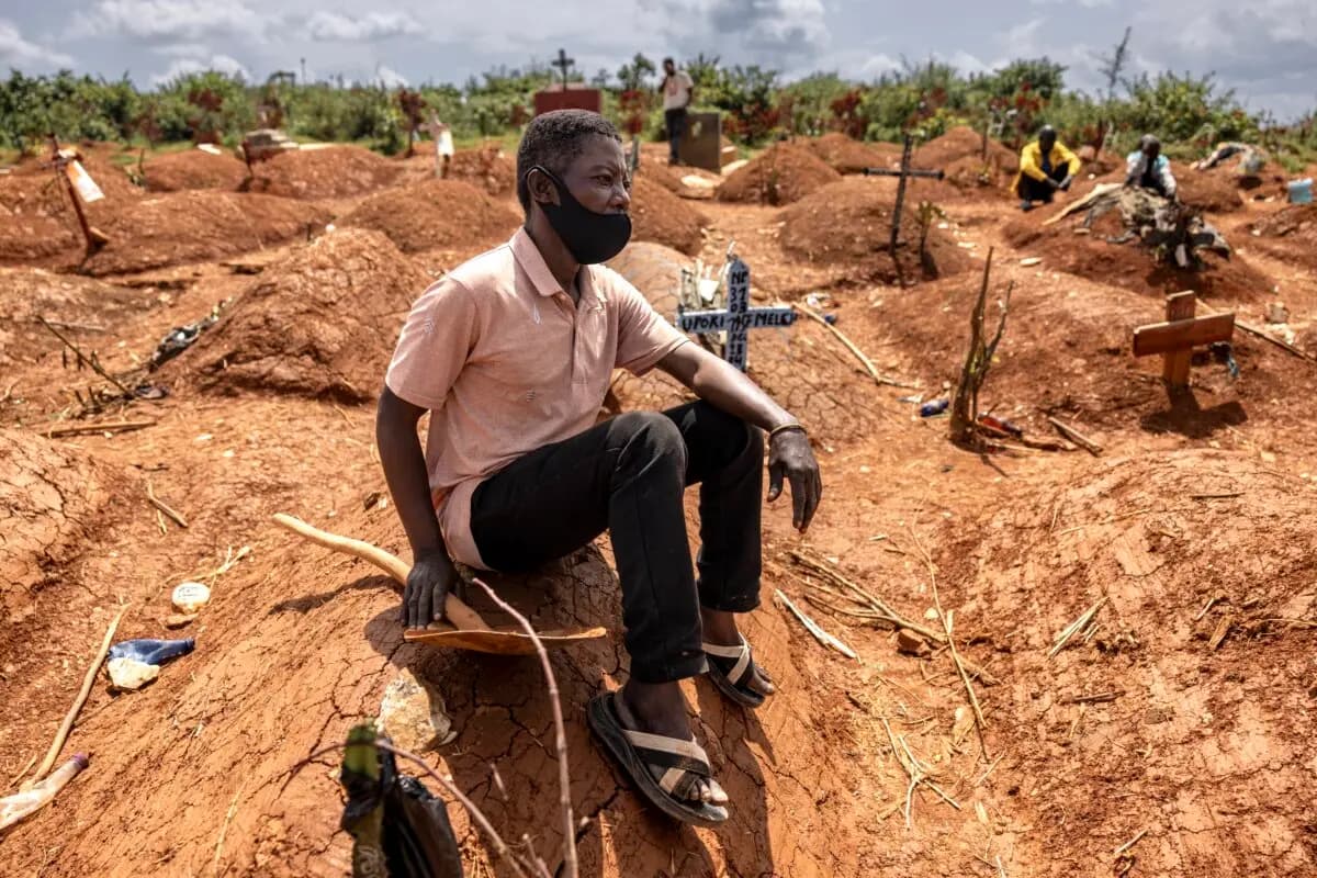 <em>Bora Moise se sienta junto a la tumba durante el funeral de su difunto sobrino Baraka Ngaju durante el brote de ébola, en un cementerio en Mongbwalu, provincia de Ituri, Congo, el 20 de mayo de 2026. (Michel Lunanga/Getty Images).</em>
