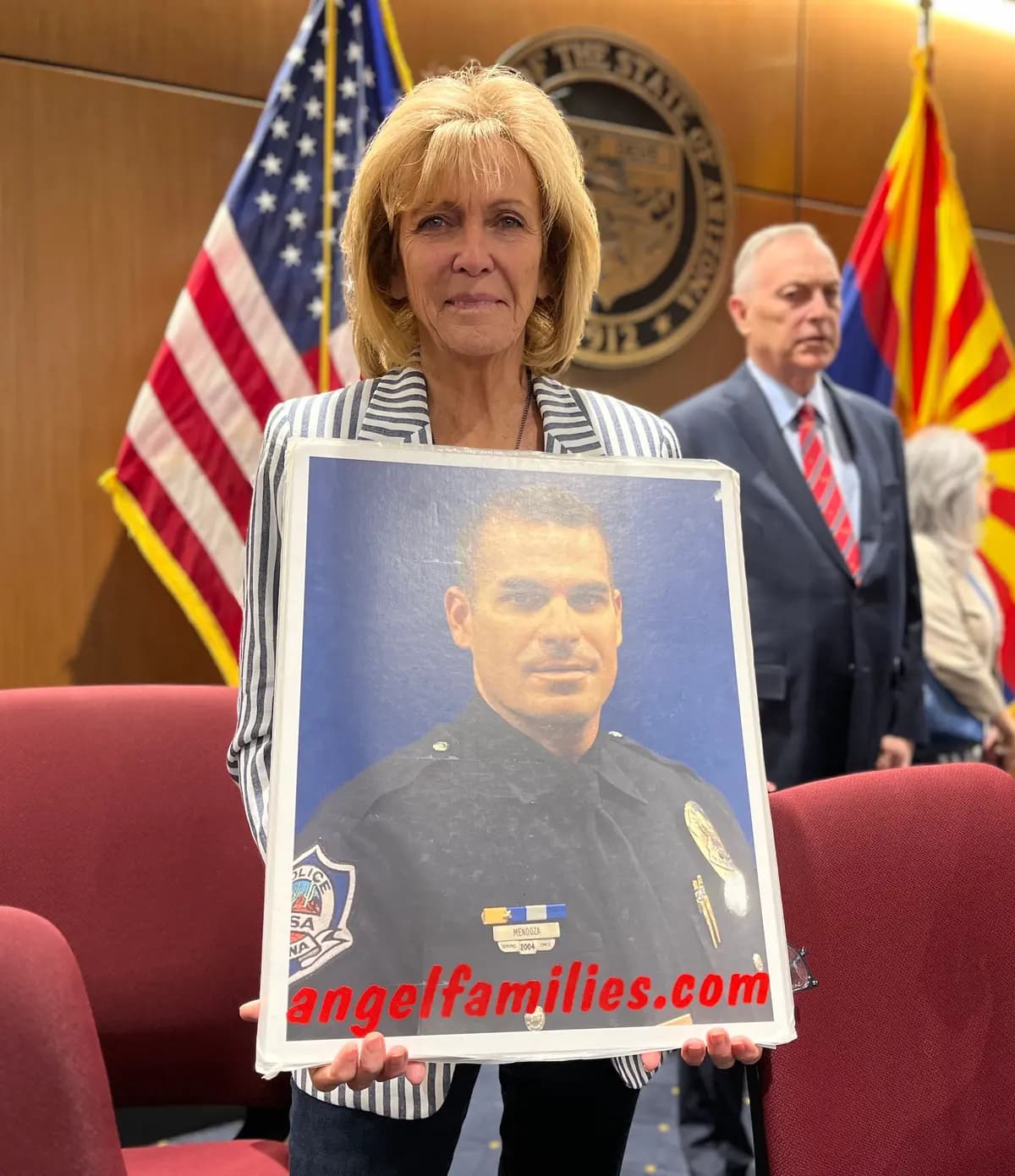 Mary Ann Mendoza sostiene una foto de su hijo, Brandon, asesinado por un conductor inmigrante ilegal en 2014. A la derecha se encuentra el congresista estadounidense Andy Biggs (R-Ariz.). (Allan Stein/The Epoch Times)