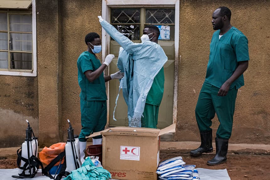 Los trabajadores de la Cruz Roja de Uganda se ponen trajes de protección mientras se preparan para evacuar el cadáver de una presunta víctima del ébola en Kampala el 26 de mayo de 2026. (Badru Katumba / AFP vía Getty Images).