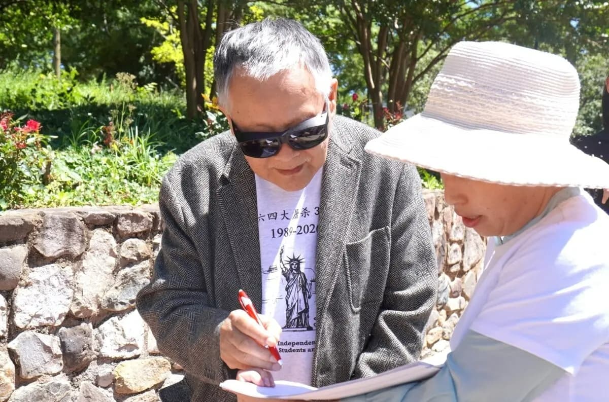 Wei Jingsheng, un destacado activista chino de derechos humanos, firma una petición en apoyo de la Ley de Protección de Falun Gong y las Víctimas de la Sustracción Forzada de Órganos, cuyo objetivo es sancionar a los responsables de la sustracción forzada de órganos sancionada por el Estado en China, frente a la embajada china en Washington el 30 de mayo de 2026. (Sherry Dong/The Epoch Times)