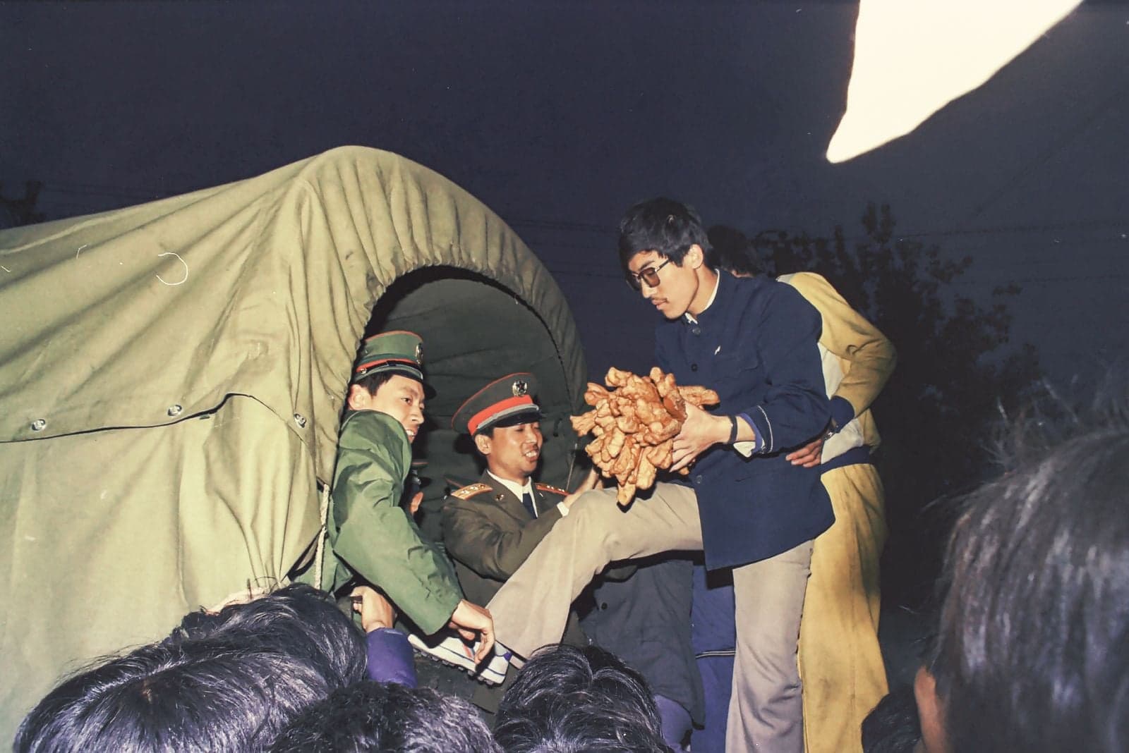 En mayo de 1989, un manifestante a favor de la democracia entrega youtiao, unos palitos de masa frita de color marrón dorado, alimento básico del desayuno en Beijing, a unos oficiales militares del lugar.