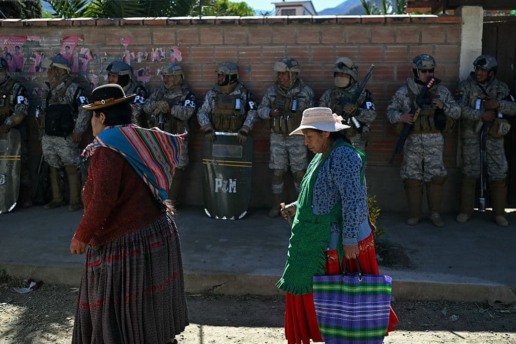 Unas mujeres pasan junto a las fuerzas de seguridad que vigilan una carretera tras su reapertura, tras las protestas que exigían la dimisión del presidente de Bolivia, Rodrigo Paz, en Carreras, departamento de La Paz, Bolivia, el 5 de junio de 2026. (Marvin RECINOS / AFP vía Getty Images)
