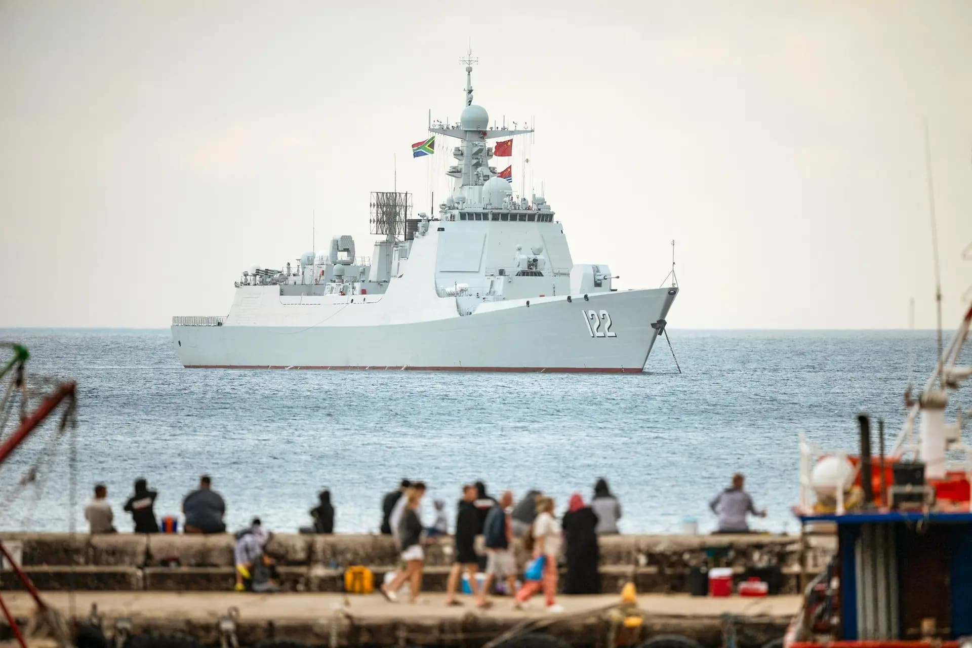 La gente pasea por el puerto de Kalk Bay mientras el destructor lanzamisiles chino Tangshan está amarrado en False Bay, cerca de Ciudad del Cabo, Sudáfrica, el 6 de enero de 2026. El dominio comercial de China en el mar podría extenderse al ámbito militar, según los analistas. (Rodger Bosch/AFP vía Getty Images)