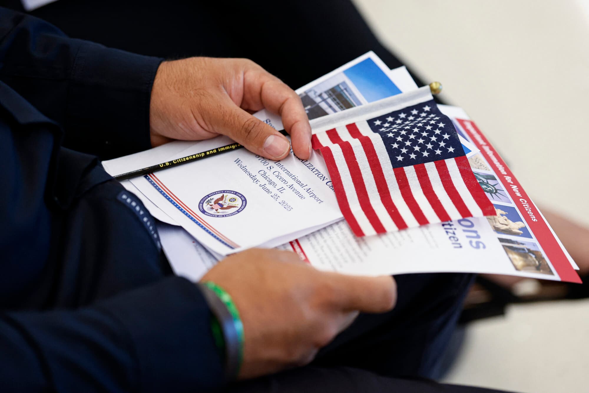 Un nuevo ciudadano estadounidense sostiene un programa mientras espera para prestar el juramento de lealtad antes de recibir su certificado de naturalización durante una ceremonia oficial en el Aeropuerto Internacional Midway de Chicago, Illinois, el 25 de junio de 2025. (KAMIL KRZACZYNSKI/AFP vía Getty Images)