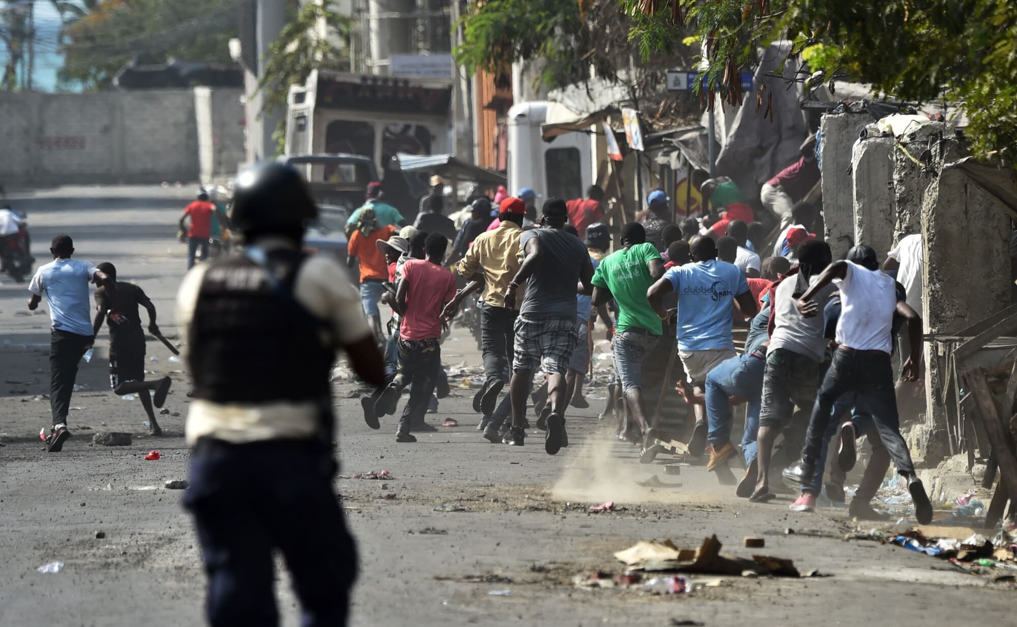 Manifestantes huyen mientras la policía haitiana dispara sus armas durante los enfrentamientos en el centro de Puerto Príncipe, la capital de Haití, el 13 de febrero de 2019. (HECTOR RETAMAL/AFP vía Getty Images)