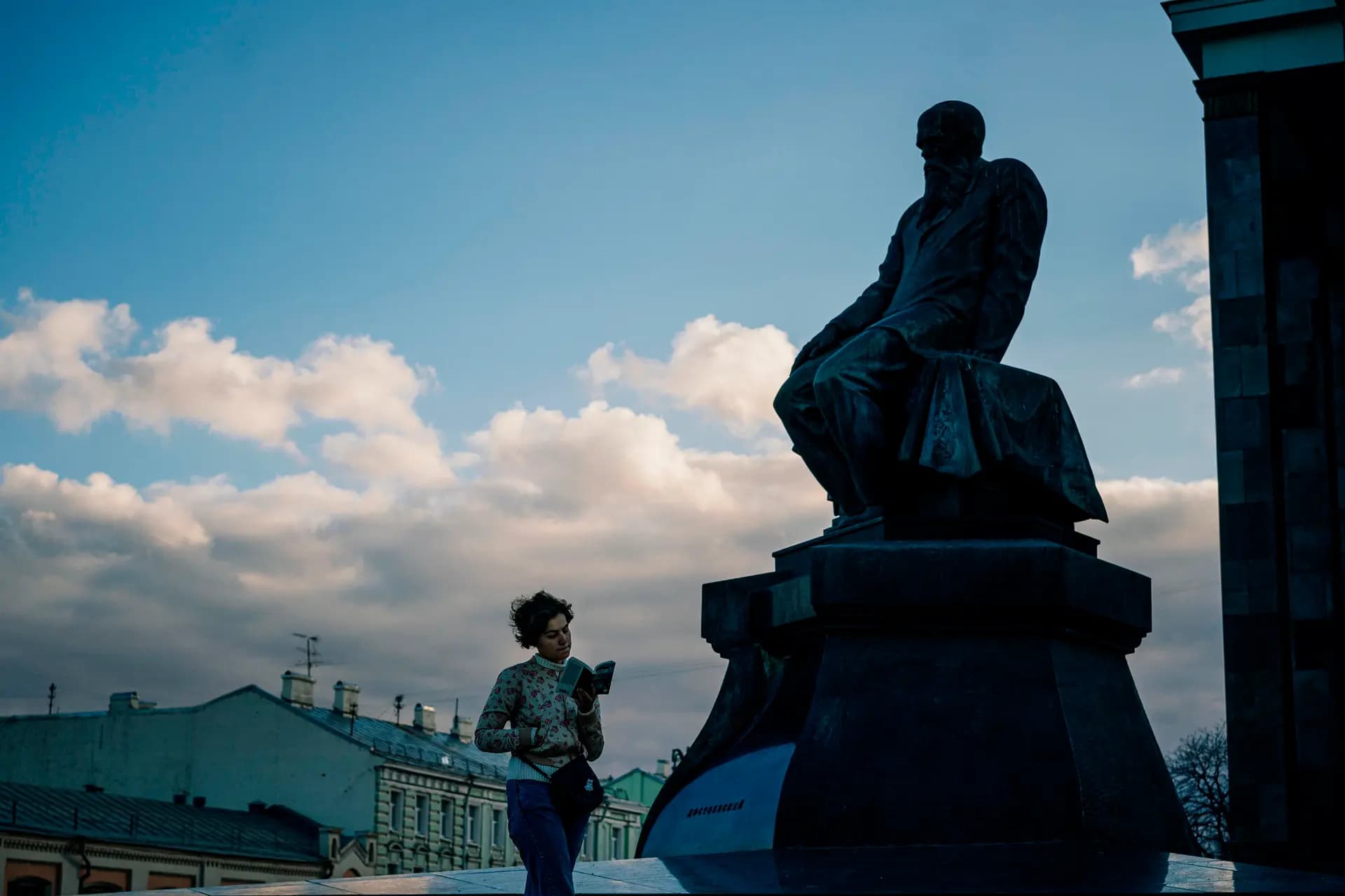 <em>Una mujer lee un libro mientras camina junto a un monumento al escritor ruso Fiódor Dostoievski en el centro de Moscú el 23 de octubre de 2019. (Dimitar Dilkoff/AFP vía Getty Images).</em>