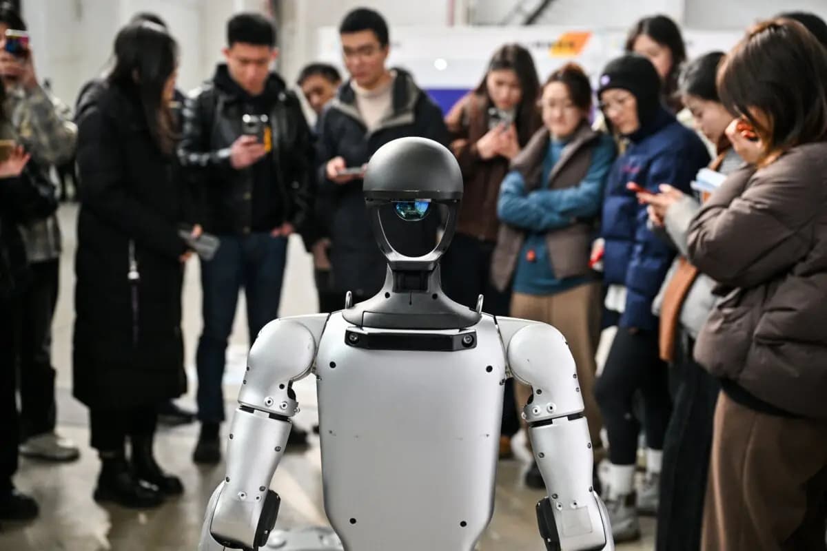 Personas junto a un robot humanoide en una conferencia sobre IA en Shanghái el 21 de febrero de 2025. (Héctor Retamal/AFP vía Getty Images)