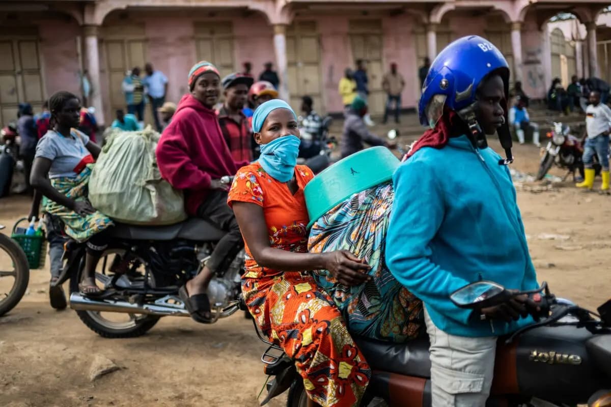 <em>Conductores de mototaxis y sus pasajeros esperan en la entrada del mercado central mientras los trabajadores sanitarios desinfectan la zona, y la provincia de Ituri continúa combatiendo un brote de ébola en Bunia, Congo, el 23 de mayo de 2026. (Moses Sawasawa/AP).</em>