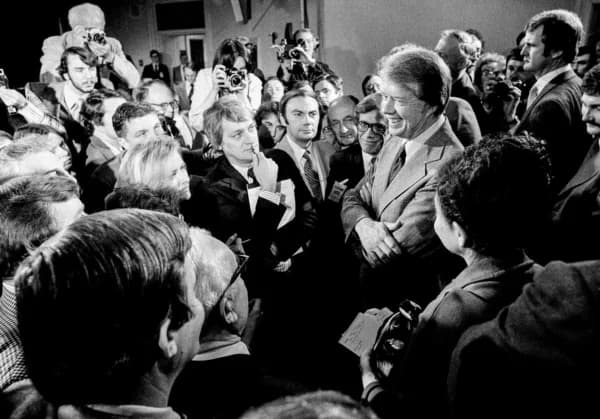El presidente Jimmy Carter (dcha.) está rodeado de periodistas tras una rueda de prensa en la que anunció el levantamiento de la prohibición de viajar a Cuba, Vietnam, Corea del Norte y Camboya, en el edificio de oficinas ejecutivas en Washington el 9 de marzo de 1977. Carter intentó normalizar las relaciones con Cuba poco después de asumir la presidencia en 1977. (Foto de archivo/AP.)