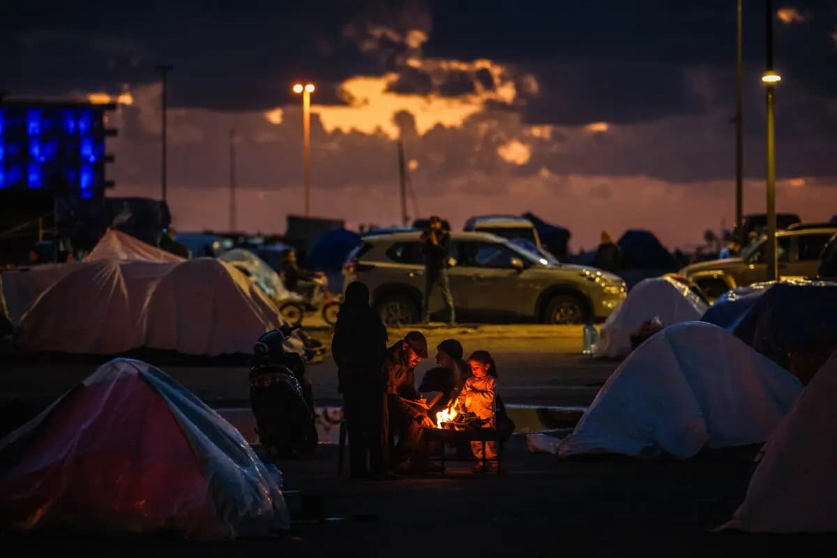 Unas personas desplazadas se calientan alrededor de una hoguera frente a su tienda de campaña en la zona costera de Beirut, en el Líbano, el 30 de marzo de 2026. (Dimitar Dilkoff / AFP vía Getty Images).
