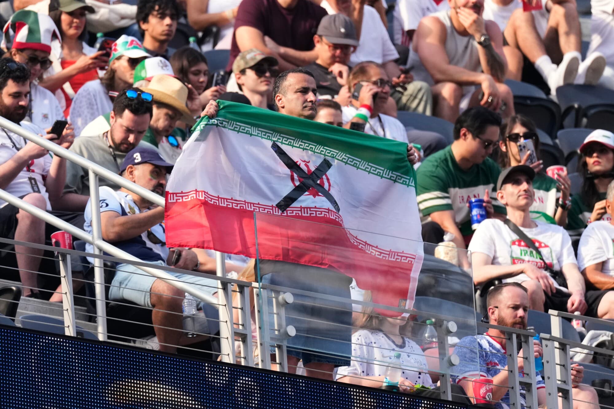 Un espectador sostiene una bandera iraní, con el símbolo de la República Islámica tachado, antes del partido de fútbol de la Copa Mundial entre Irán y Nueva Zelanda en Inglewood, California, el 15 de junio de 2026. (Mark J. Terrill/AP).