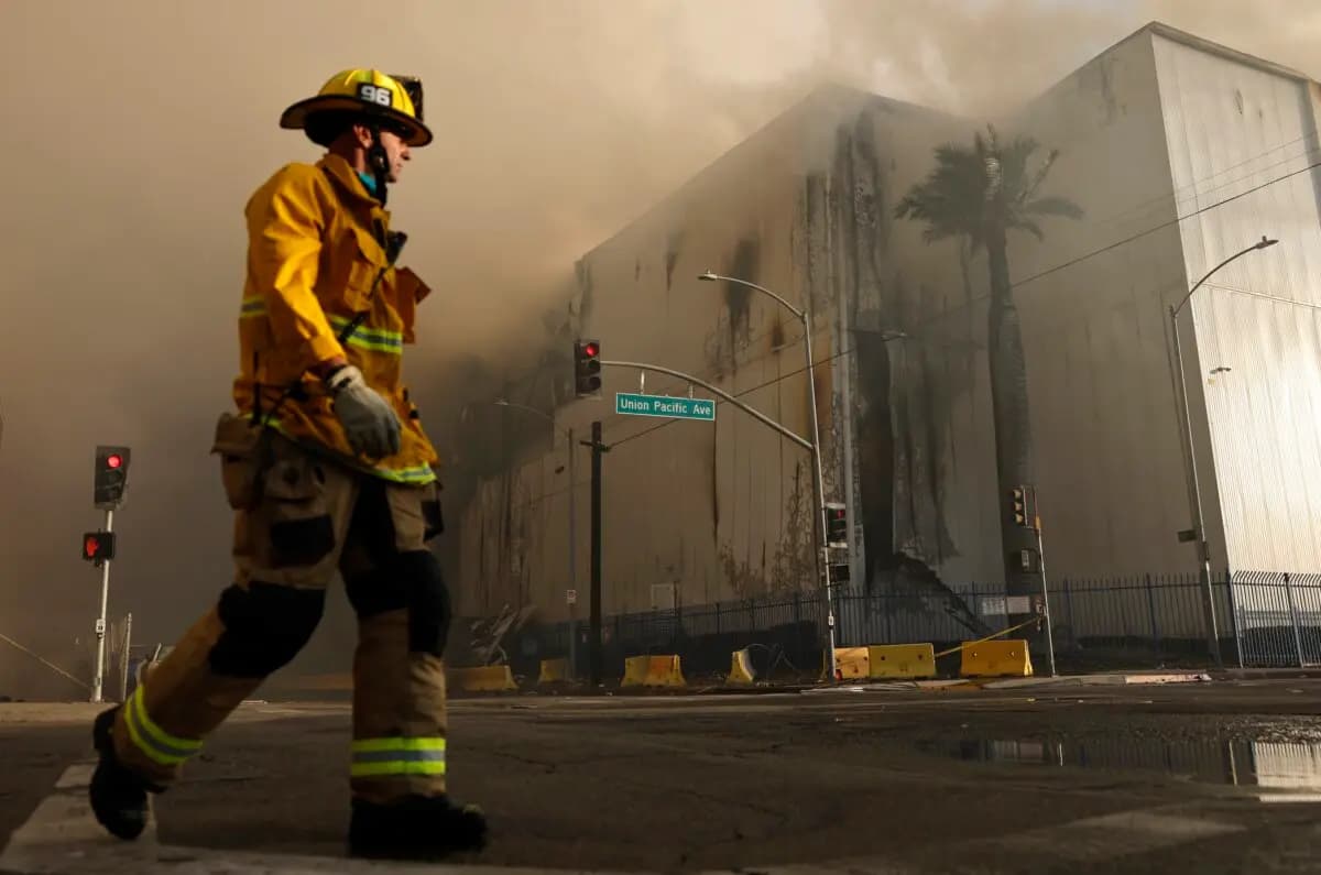 Un bombero camina por la calle mientras un enorme incendio en un almacén de almacenamiento en frío continúa ardiendo y propagando humo por la ciudad de Los Ángeles el 20 de junio de 2026. (Mario Tama/Getty Images)