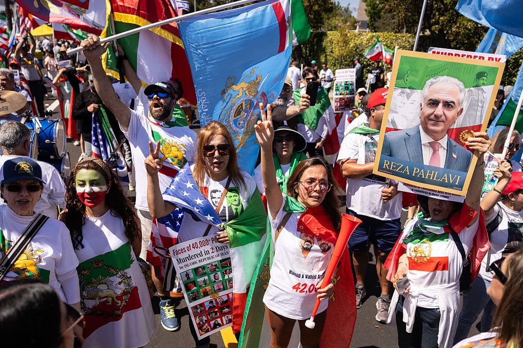 <em>Un manifestante sostiene un cartel con un retrato del hijo del último sha de Irán, Reza Pahlavi, mientras la gente se manifiesta contra el régimen iraní frente al Estadio de Los Ángeles (Estadio SoFi) antes del partido del torneo de fútbol de la Copa Mundial de 2026 entre Irán y Nueva Zelanda en Inglewood, California, el 15 de junio de 2026. Cientos de manifestantes contra el régimen se reunieron frente al estadio de Los Ángeles el lunes, donde Irán se enfrentará a Nueva Zelanda en su partido inaugural de la Copa del Mundo de 2026. (ETIENNE LAURENT / AFP vía Getty Images)</em>