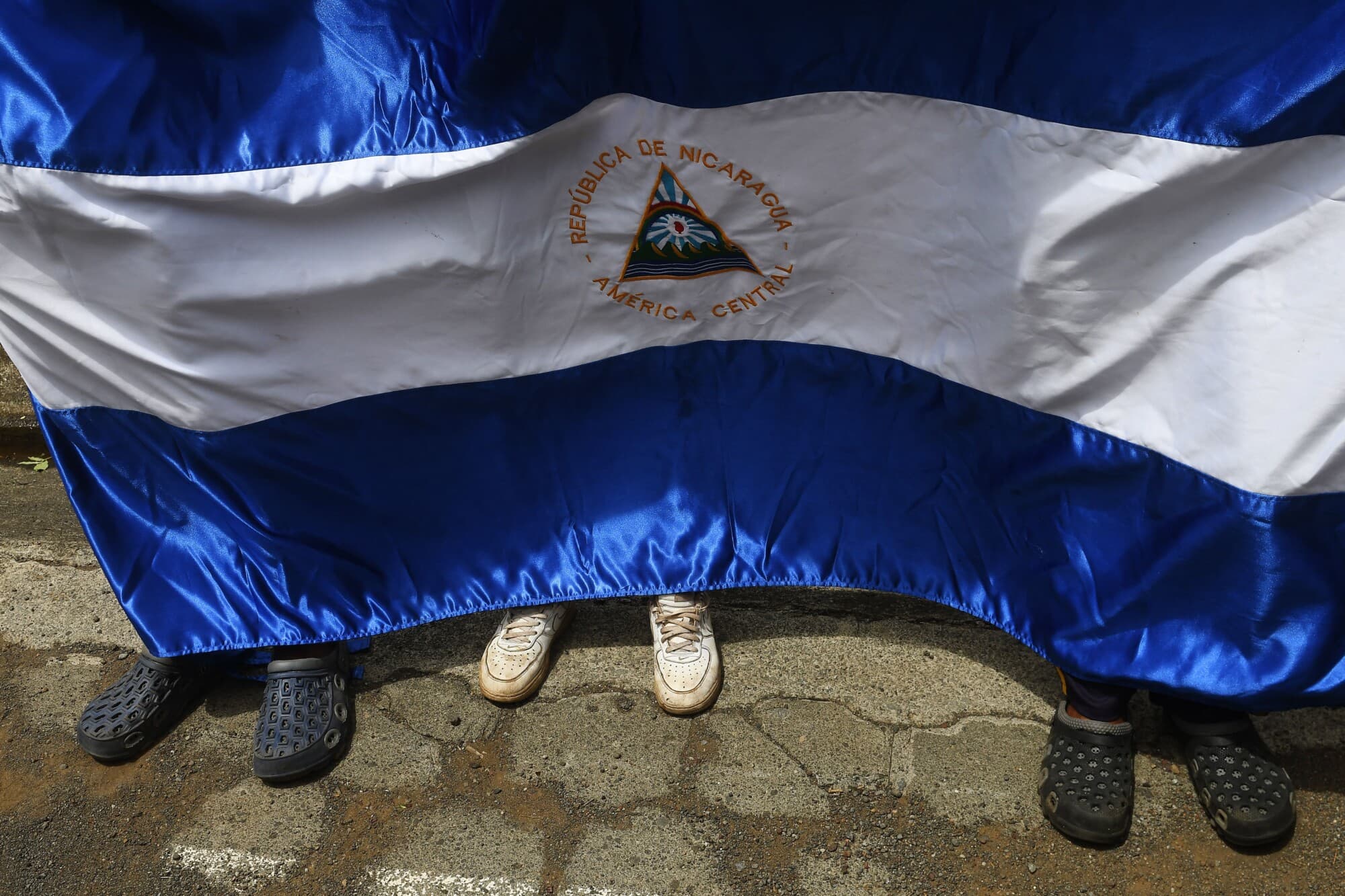Un grupo de personas exhibe una bandera nacional nicaragüense mientras los líderes de los manifestantes antigubernamentales —entre los que se incluyen grupos vecinales, estudiantiles y campesinos— ofrecen una rueda de prensa para denunciar el uso excesivo de la fuerza por parte de la policía y los paramilitares en la represión ejercida contra ellos durante protestas contra el presidente nicaragüense Daniel Ortega, que saldaron más de 200 muertos, en Managua, el 27 de junio de 2018. (MARVIN RECINOS/AFP vía Getty Images)