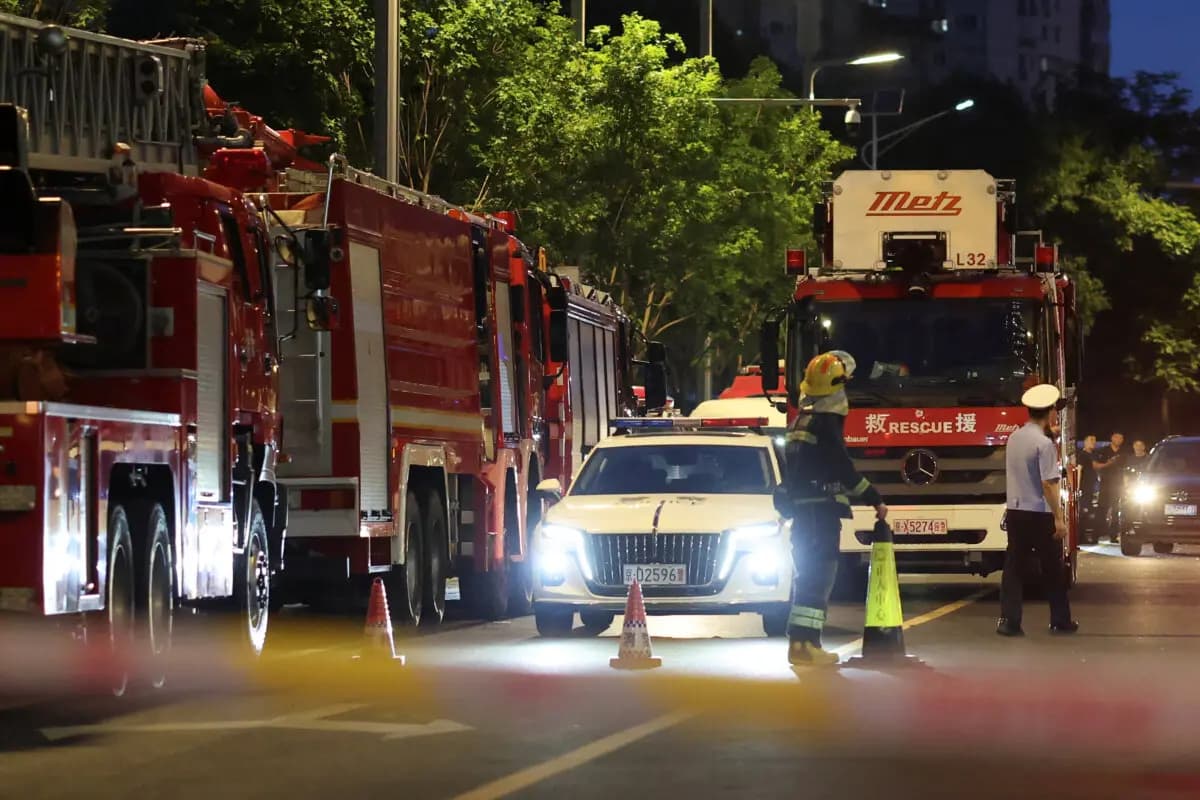 <em>Personal de rescate se encuentra cerca de camiones de bomberos detrás de un cordón policial en una carretera junto a la Torre CITIC en Beijing, el 26 de junio de 2026. (Maxim Shemetov/Reuters)</em>