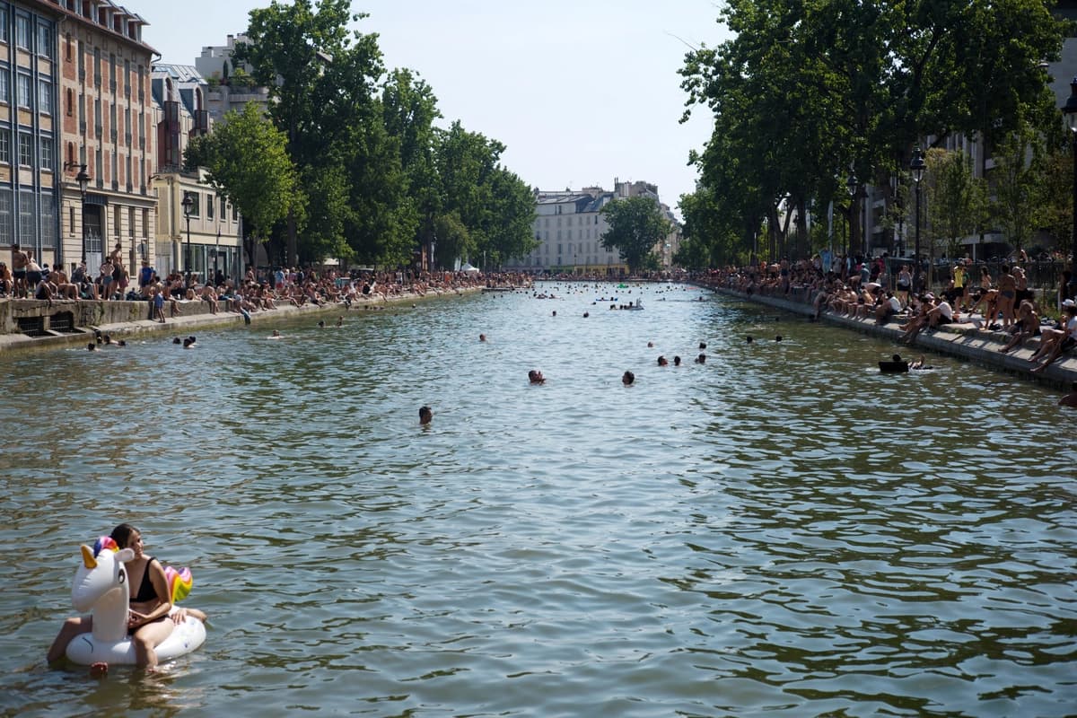 Parisinos nadando en el Canal Saint-Martin durante la ola de calor que azotó París el 27 de junio de 2026. (Brune Simon/Hans Lucas vía AFP vía Getty Images)