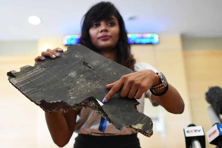 Grace Subathirai Nathan (derecha), hija de Anne Daisy, pasajera del vuelo MH370 de Malaysia Airlines, muestra un fragmento de escombros que se cree que pertenece al vuelo MH370 durante una conferencia de prensa en Putrajaya el 30 de noviembre de 2018. (MOHD RASFAN/AFP vía Getty Images)