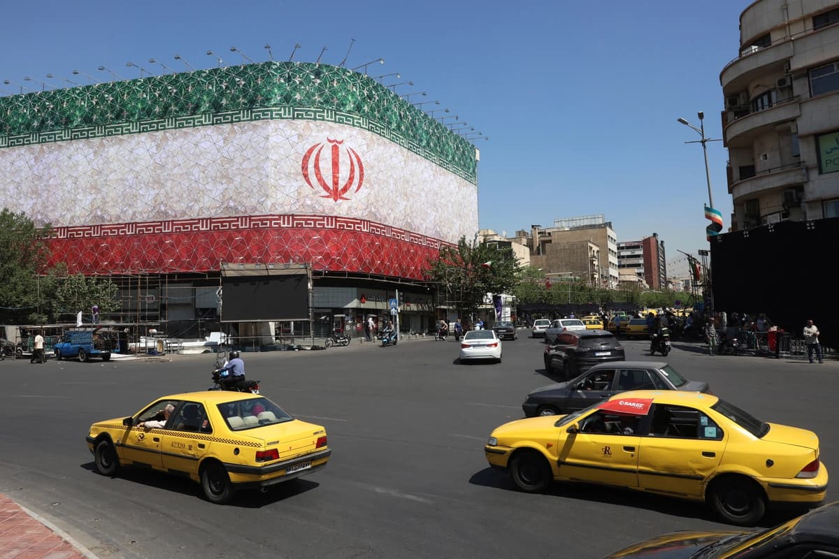El tráfico pasa junto a la bandera nacional iraní exhibida en un edificio de la plaza Enghelab en Teherán el 14 de junio de 2026. (AFP vía Getty Images)