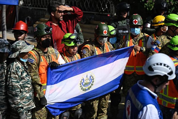 <em>Rescatistas de El Salvador sostienen su bandera nacional frente al edificio del que más tarde fue rescatado Hernán Gil, en Catia La Mar, estado La Guaira, Venezuela, el 2 de julio de 2026, ocho días después del doble terremoto. Cientos de rescatistas en Venezuela celebraron y se abrazaron el 2 de julio de 2026 tras sacar con vida a Hernán Gil, de 43 años, de las ruinas de un edificio colapsado, ocho días después de los mortíferos seísmos, según constataron periodistas de AFP. (Foto de Federico Parra/AFP vía Getty Images)</em>