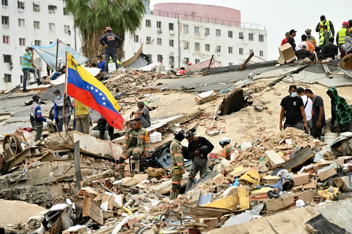 Los rescatistas y voluntarios trabajan entre los escombros de edificios derrumbados, mientras se iza una bandera venezolana, en Caraballeda, estado de La Guaira, Venezuela, el 3 de julio de 2026. (Martin Beretti / AFP vía Getty Images)